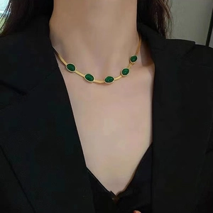 Detail einer goldenen Schlangenkette mit fünf smaragdgrünen ovalen Steinen am Modell