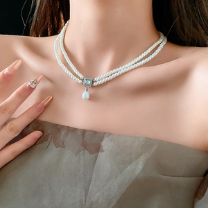 Detail of double-layer pearl necklace with a square blue gemstone and teardrop pearl
