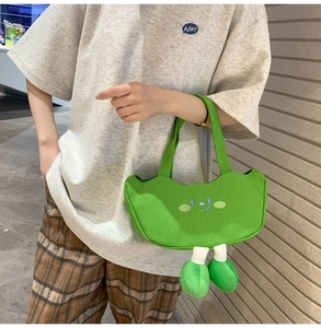 Close-up of green canvas bag with embroidered face and 3D plush feet detail