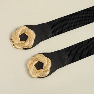 Detail of interlocking gold geometric buckle with textured finish on black elastic belt