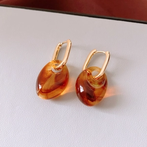Macro shot of vintage resin amber pendant earrings with golden metal clasps on white