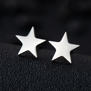 Macro shot of polished silver star earrings on a premium black leather texture background
