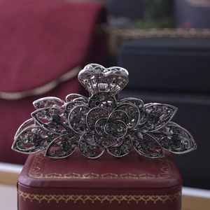 Detail shot of vintage hollow floral hair claw clip with dark rhinestones on red box