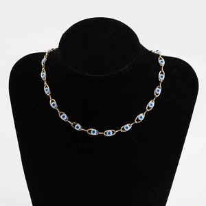 Golden stainless steel chain necklace with blue evil eye beads on a black mannequin