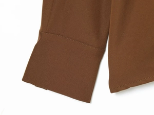 Gros plan détaillé des poignets en sergé marron montrant les coutures et la texture