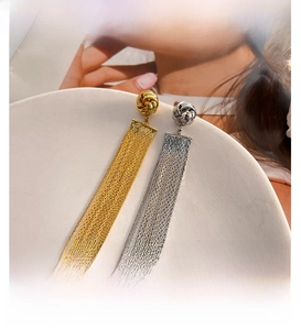 Close-up of gold and silver long chain tassel earrings with woven knot detail