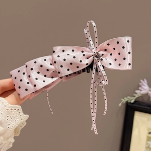 Détail d'une barrette à cheveux nœud rose satiné à pois noirs et centre en cristal