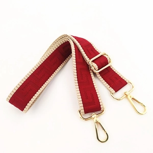 Close-up of red geometric woven bag strap with golden metal swivel hooks and adjuster
