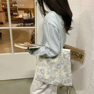 Detail of light blue floral lace tote bag with delicate texture and long shoulder strap