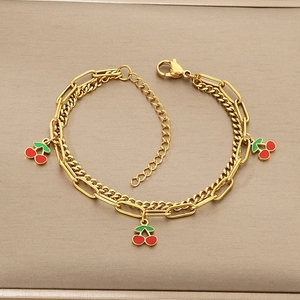 Close-up of double-layer gold chain bracelet with three red cherry enamel pendants
