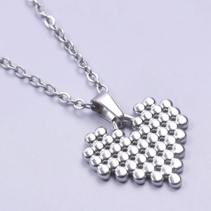 Macro shot of a silver heart pendant with beaded texture on a stainless steel chain