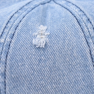 Macro di tessuto denim lavato azzurro con dettagli di cuciture bianche sfilacciate e usurate