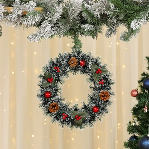 Detailed view of Christmas wreath with snowy pine needles, red berries, and natural cones