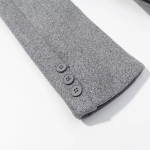 Detail view of a grey wool coat sleeve featuring three matching buttons and premium texture