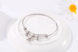 Detail of adjustable silver guitar bangle with polished beads on white ceramic tray