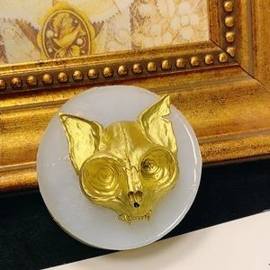 Artistic golden cat skull sculpture on round white base with vintage frame background