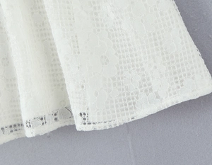 Close-up detail of white lace fabric with intricate floral patterns and fine mesh texture