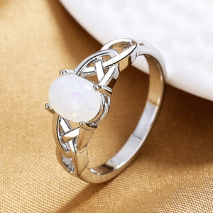 Macro shot of silver ring featuring white opal stone and Celtic knot weave design