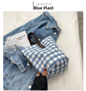 Close-up of blue gingham bucket bag with premium brown leather handle and metal rivets