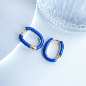 Detail of U-shaped gold earrings with vibrant blue enamel finish on white background