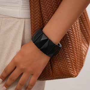 Detail of a minimalist black geometric resin cuff bracelet on woman's wrist