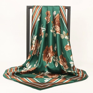 Deep green satin silk square scarf with floral pattern and striped edges on a display stand