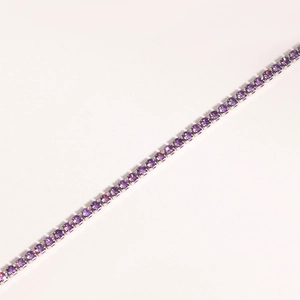 Close-up of a silver tennis bracelet with single-row four-prong set purple zircons