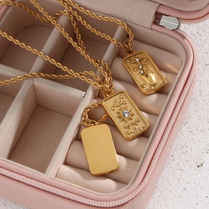 Golden tarot card necklaces with embossed sun and star designs in a pink jewelry box