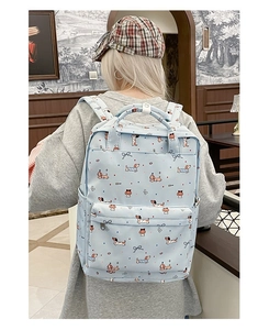 Detail of light blue graffiti backpack featuring cartoon dachshund prints and large capacity