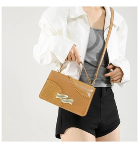Detailed view of brown crossbody bag featuring crocodile texture and gold hardware