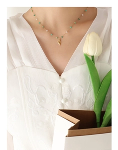 Detail of tulip pendant necklace with green crystal beads on elegant model in white