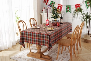 Detailed close-up of a festive red and green plaid tablecloth on a wooden dining table