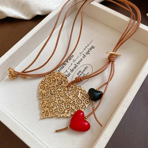 Detail of hollow heart pendant on long leather cord with red and black beads