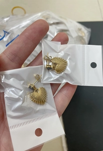 Close-up of golden heart-shaped earrings in plastic packaging with stainless steel detail