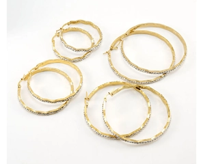 Detail of four pairs of gold-plated hoop earrings with wavy edges and sparkling rhinestones