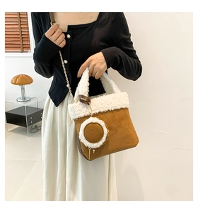 Detail of brown suede bucket bag with white faux fur trim and gold chain strap