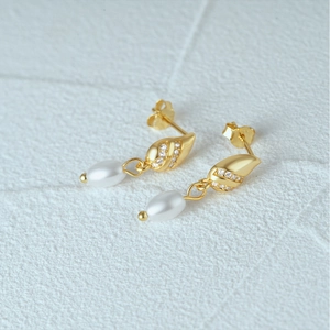 Detail of s925 silver twist gold earrings with white zircons and oval pearls