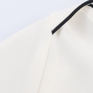 Macro-opname van de witte stoftextuur met zwarte gevlochten biesdetails op de naad