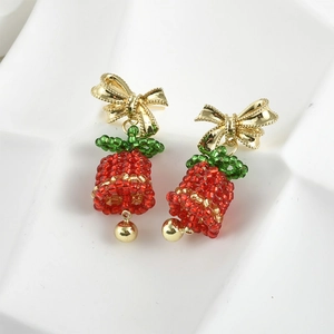 Christmas tree earrings with golden bows and red green beaded bells on white tray
