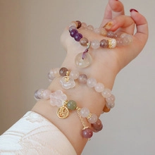 Detailed view of layered freshwater pearl bracelets with floral and Fu character charms