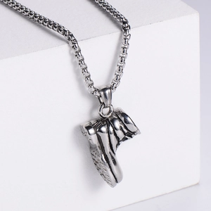 Macro detail of vintage silver stainless steel work boot pendant on a squared box chain