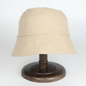 Detailed texture of a beige cotton bucket hat on a wooden stand with visible stitching