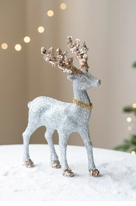 Macro shot of silver glitter reindeer statue with gold sequins in festive scene