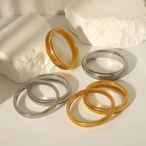 Close-up of gold and silver snake bone texture bracelets on a white textured rock
