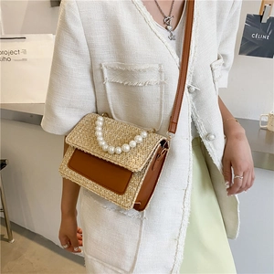 Straw crossbody bag with pearl handle and brown leather trim for summer beach vacation