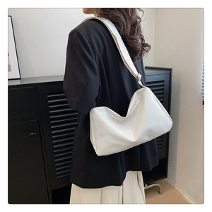 Detail of white soft faux leather tote bag showing smooth texture and wide strap