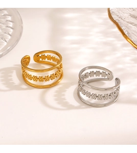 Detail of layered stainless steel rings with floral pattern in gold and silver finish