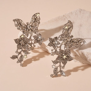 Detail von silbernen Schmetterlings-Ohrclips mit Kristallen auf einem Naturstein