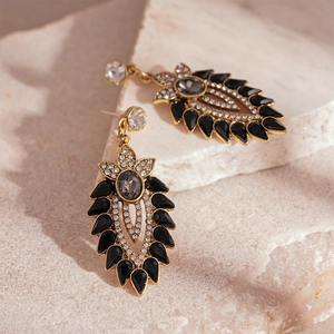 Vintage gold earrings with dark gems and sparkling floral leaf design on stone