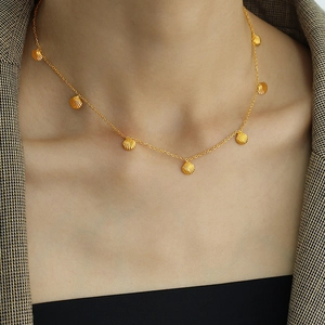 French style shell pendant necklace in gold, elegantly worn on a stylish grey plaid blazer